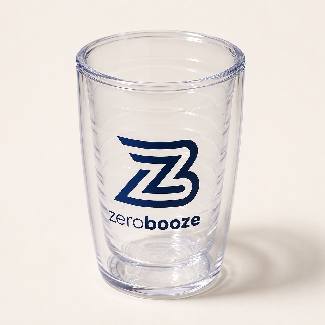 Clear Zero Booze double-wall tumbler with navy ZB branding on a warm-white background